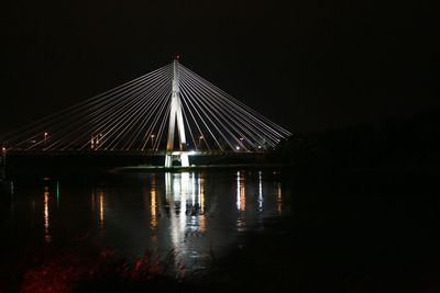 Illuminated bridge against sky at night