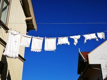 Low angle view of clothesline hanging against blue sky