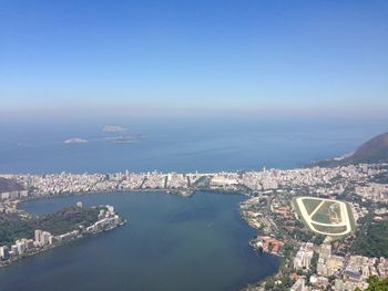 High angle view of cityscape by sea against clear sky