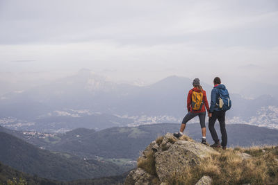 Mature man and woman holding hands standing on rock