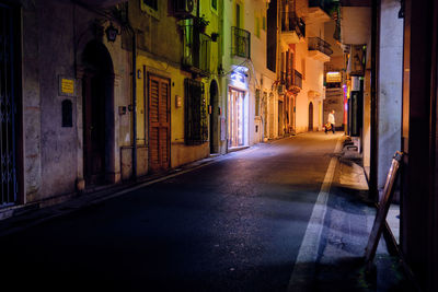 Narrow street amidst buildings in city at night