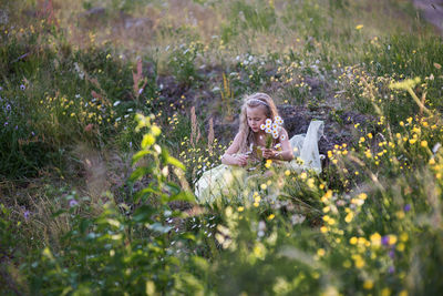 Girl plucking flowers on field