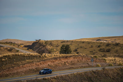 Car on road by land against sky