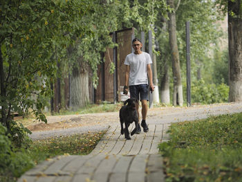 A young man of european appearance walks his dog in the park in the summer. high quality photo