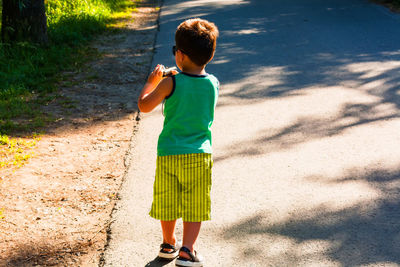 Full length of boy standing on road during sunny day