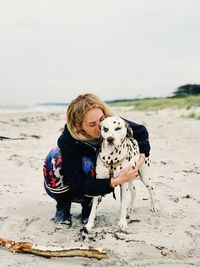 Woman with dog on beach against sky