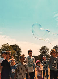 People playing with bubbles against sky