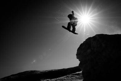 Low angle view of woman jumping against sky