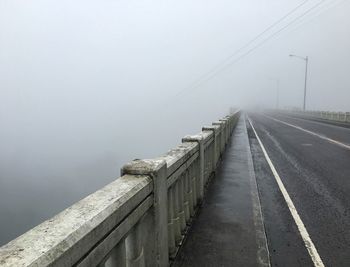 Bridge over foggy weather against sky during winter