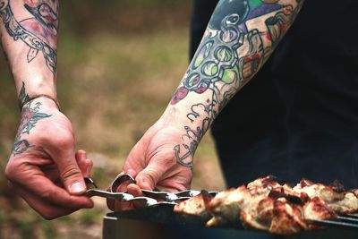 Tattooed hands grilling meat