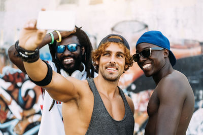 Happy friends taking selfie while standing outdoors