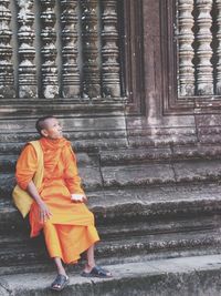 Full length of man sitting outside building