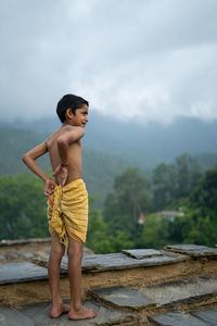 A young indian cute kid doing yoga in the mountains,wearing a dhoti