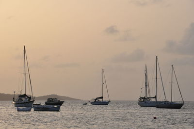 Sailboats in sea against sky at dusk