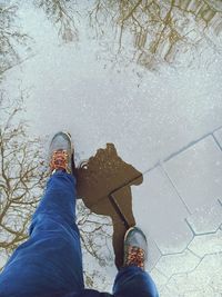 Reflection of man in puddle while standing on paving stone