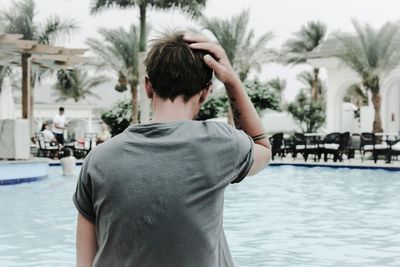 Rear view of boy standing by swimming pool