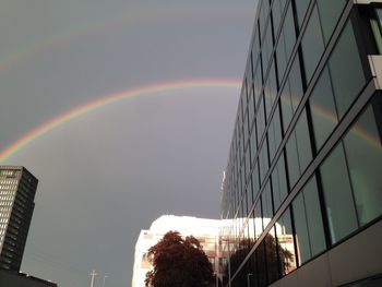 Low angle view of rainbow over buildings against sky