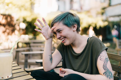 Portrait of young woman using mobile phone while sitting on table