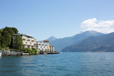 Sea by mountain against blue sky