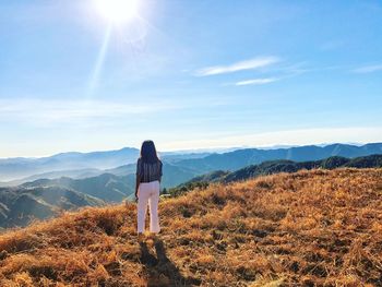 Rear view of woman standing on mountain against sky