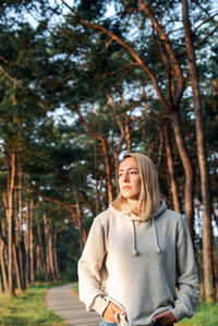 Portrait of a young blond woman walking in a pine forest at dawn.