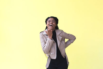 Smiling man standing against yellow background