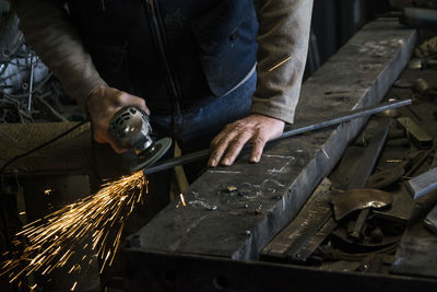 Midsection of man welding metal at workshop