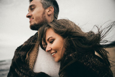 Portrait of young woman looking away against sky during winter