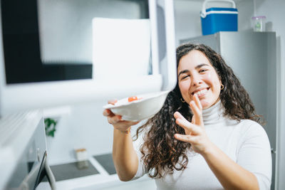 Portrait of young woman opening microwave open