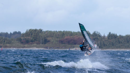 Man surfing in sea against sky