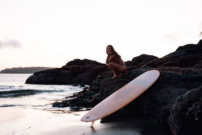 Beautiful, fit woman with surfboard on beach in tofino