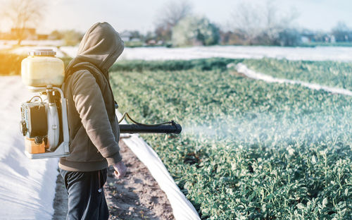 A man sprays a farm field. protection of plants. pesticides and fugicides in agroindustry. 