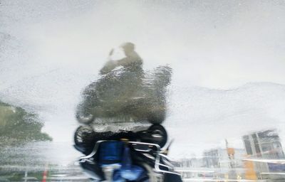 Reflection of man in car against sky