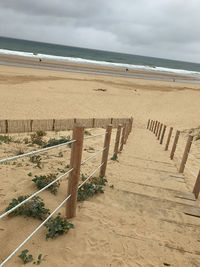 Wooden posts on beach against sky