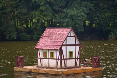 Wooden post by lake against trees and plants