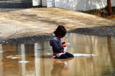 Full length of girl sitting in puddle on road