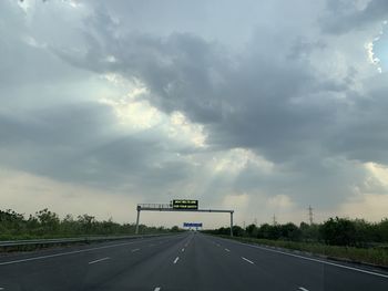 Road sign on highway against sky