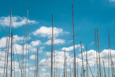 Low angle view of boat masts against blue sky