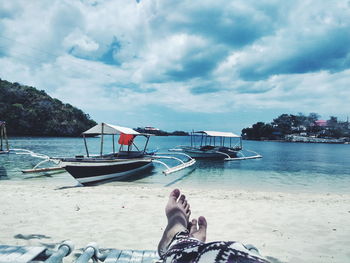 Low section of man on beach against sky