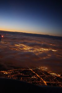 Aerial view of illuminated city against sky at sunset