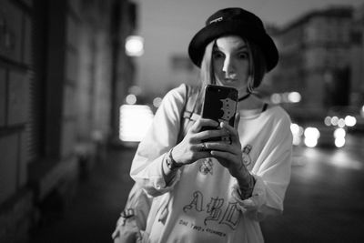 Young woman taking selfie from mobile phone on street at night