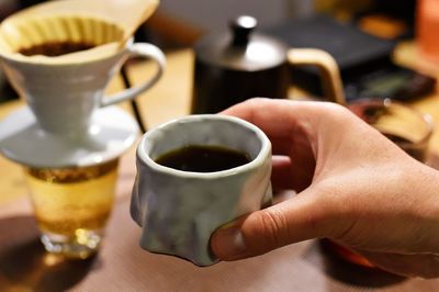 Midsection of person holding coffee cup on table