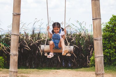 Full length of girl swinging at playground