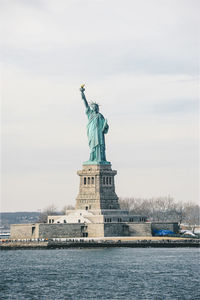 Statue of liberty and upper bay against cloudy sky