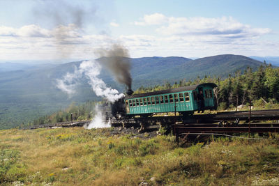 Steam train of mount washington cog railway is pusing up coach to summit at good weather conditions