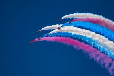 Low angle view of airshow against blue sky