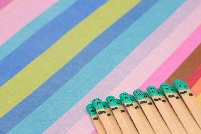 Matchsticks with faces painted on the heads on multicolored paper