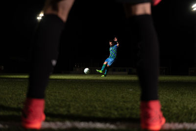 Crop anonymous goalkeeper protecting goal while rival player kicking ball during match on field