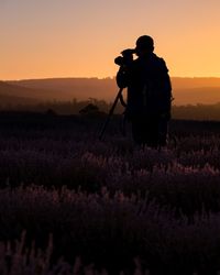 Rear view of man photographing at sunset