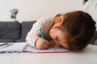 Portrait of cute preschooler child girl drawing with pencils at home while sitting